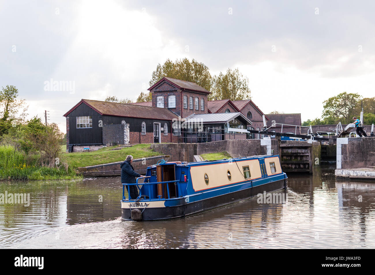A narrowboat traversing Hatton Locks on the Grand Union Canal with visitor centre in background, Warwickshire, United Kingdom Stock Photo