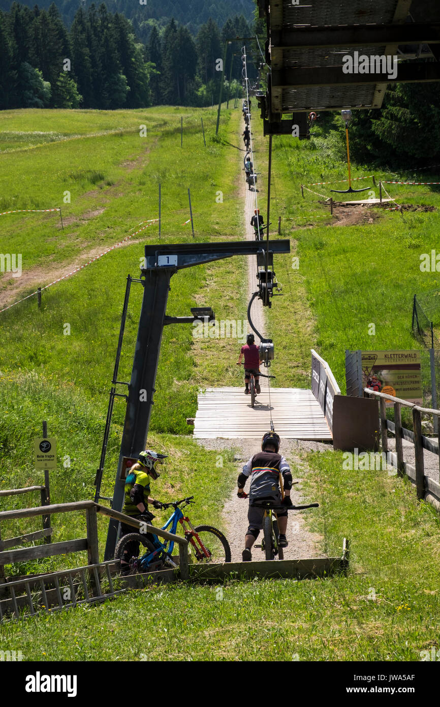 Offroad mountain bikers using the Kletterwald skilift to take them uphill to the start of their downhill bike track, Oberammergau, Garmisch Partenkirc Stock Photo