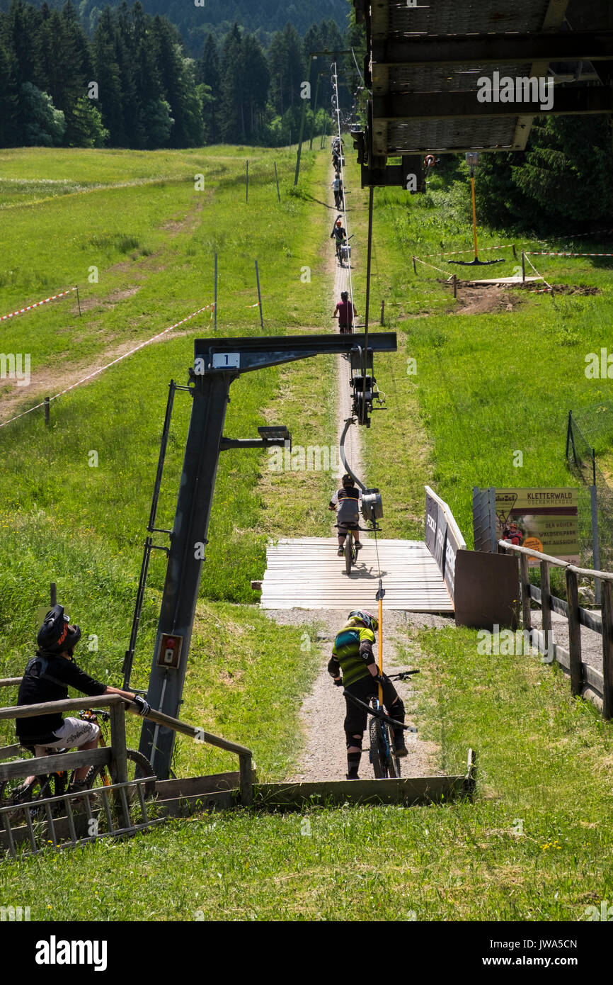 Offroad mountain bikers using the Kletterwald skilift to take them uphill to the start of their downhill bike track, Oberammergau, Garmisch Partenkirc Stock Photo