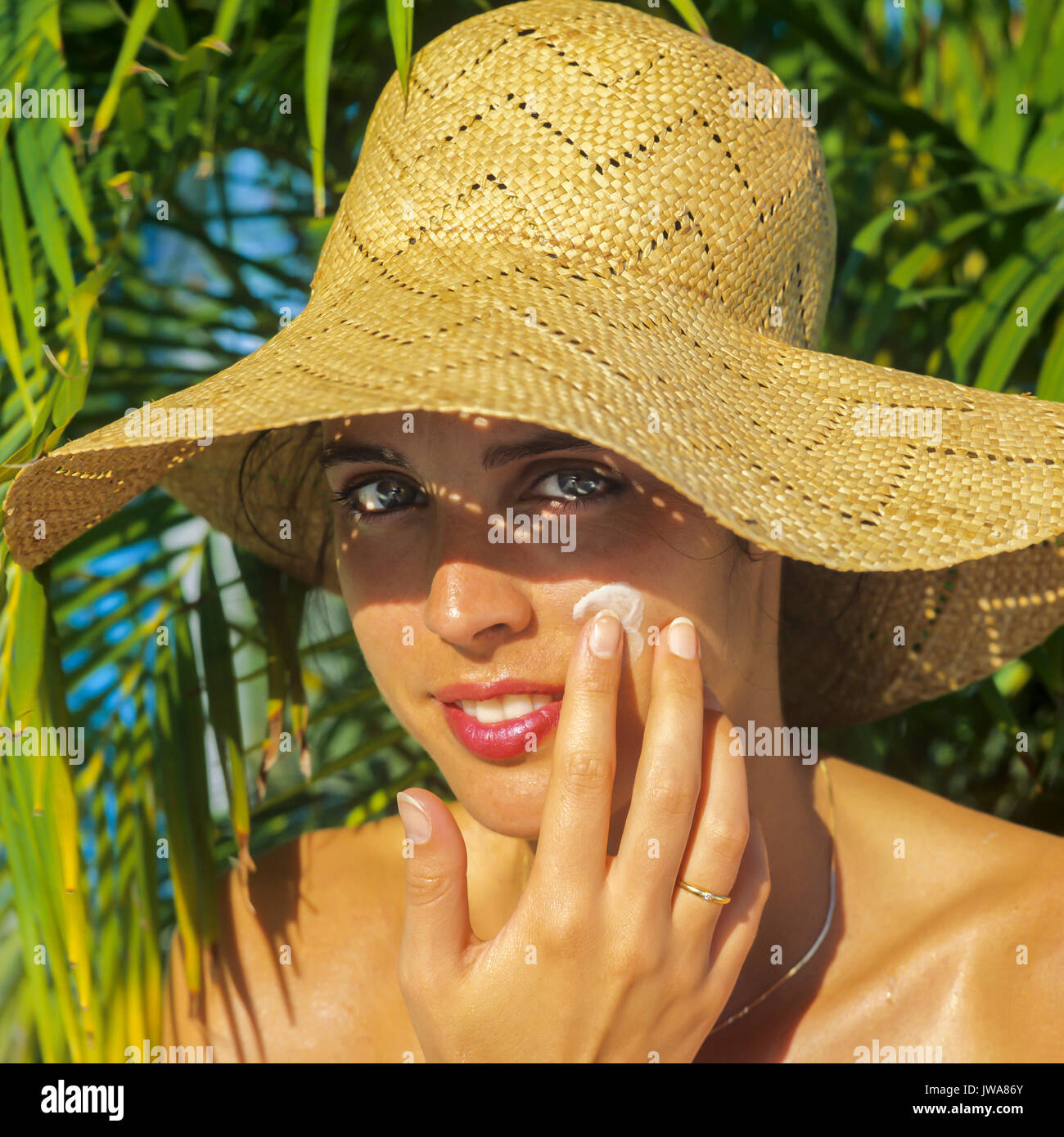 sunhat, applying sun cream on her face 