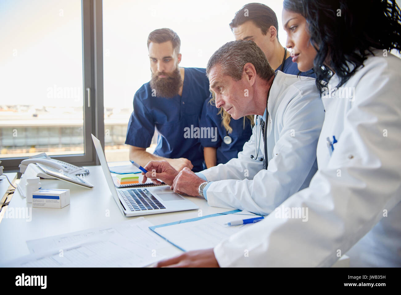 Team of doctors at a meeting in a hospital looking at a laptop Stock Photo