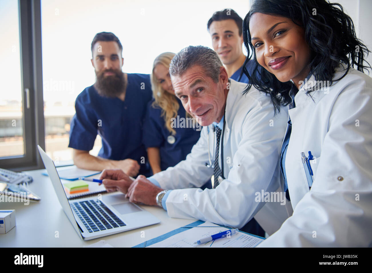 Team of multi ethnic doctors at hospital holding a meeting around a desk Stock Photo