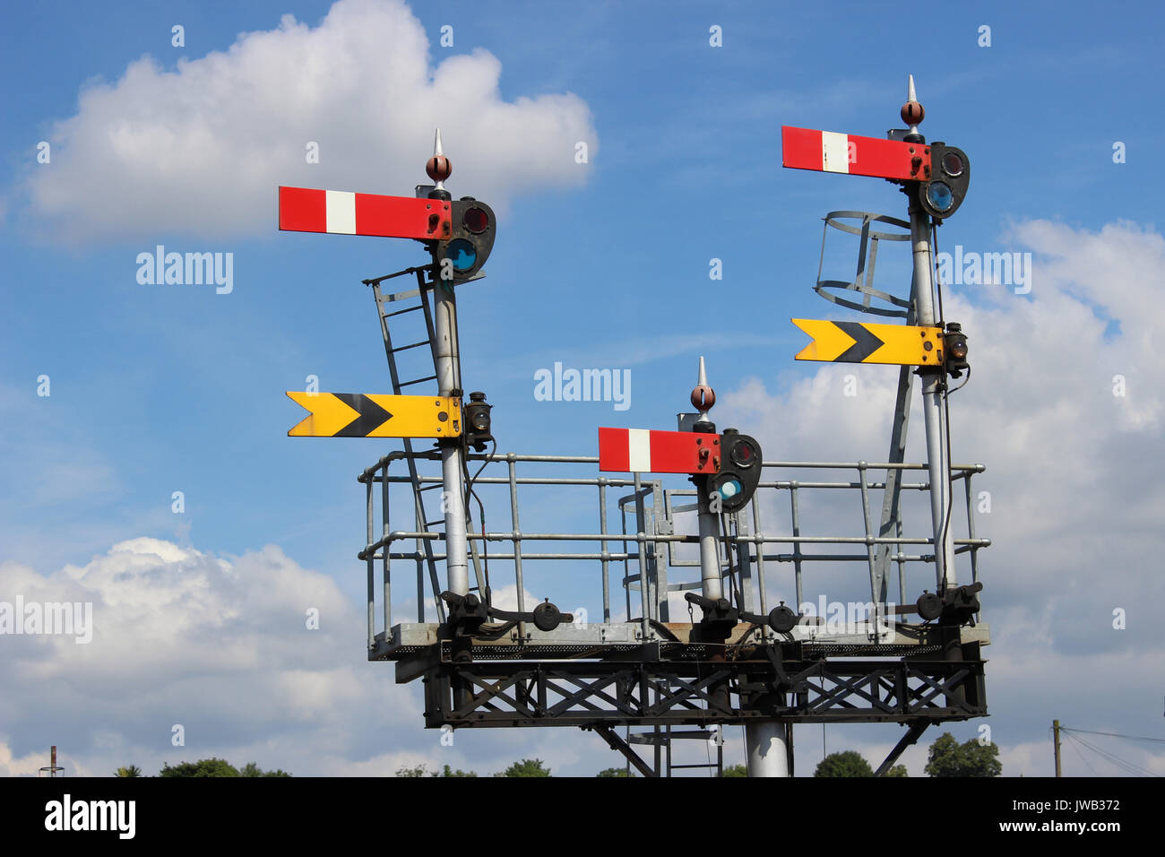 Set of semaphore signals on a gantry at one end of Worcester Shrub Hill railway station seen against a mainly blue sky. Stock Photo