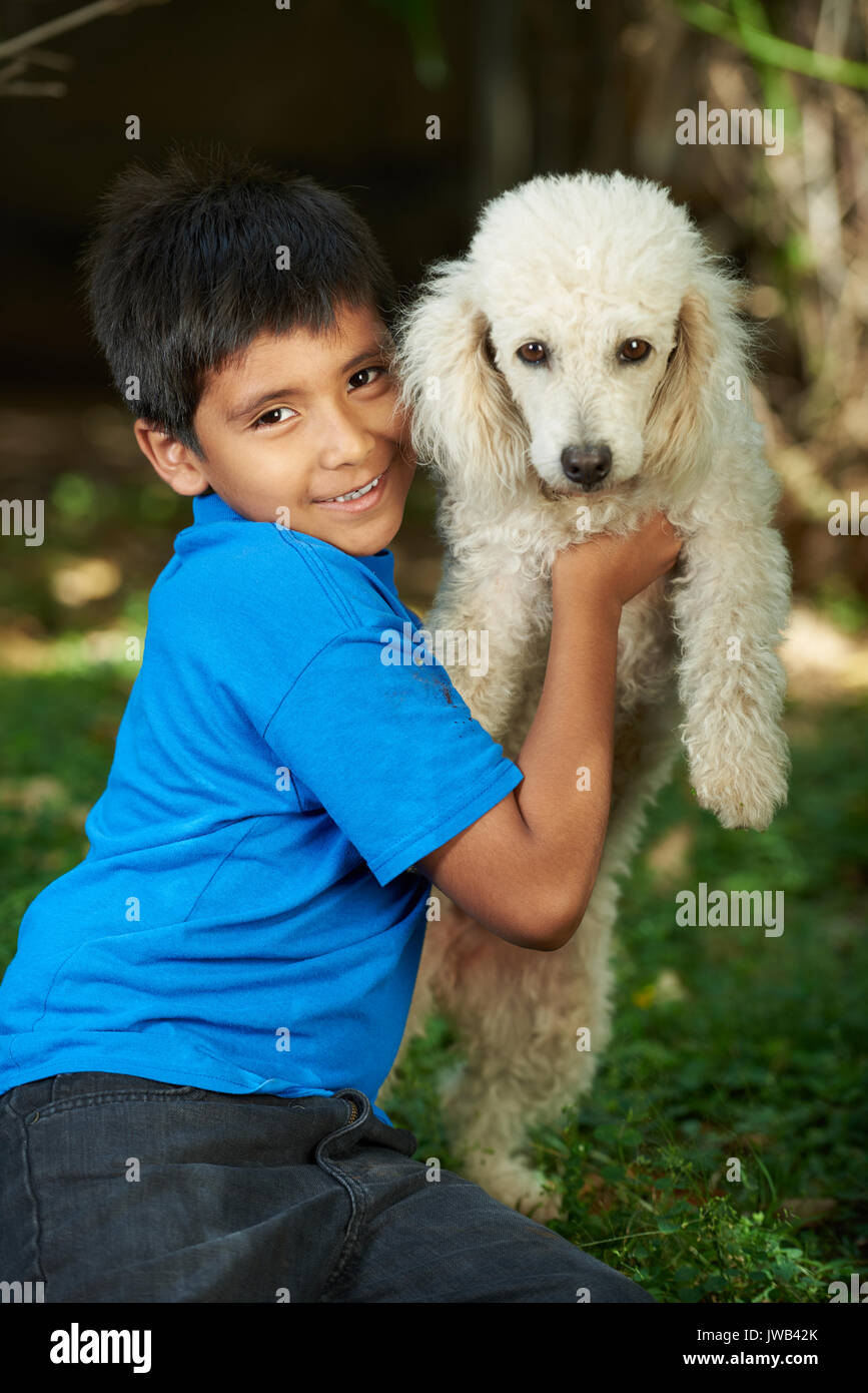 Small smiling boy with poodle dog on sunny light park background Stock Photo