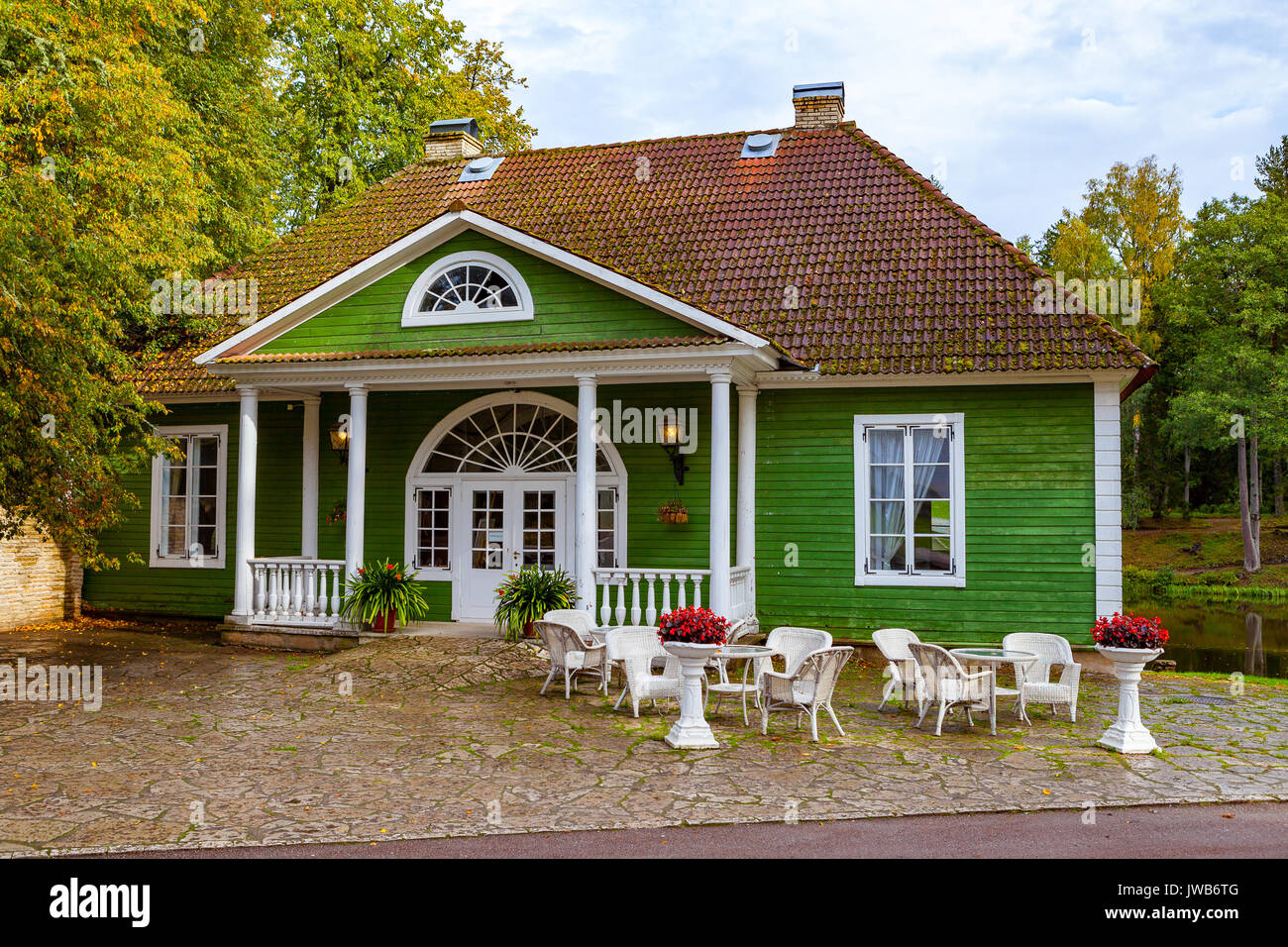 Green wooden house - cafe with tables and chairs outdoor in park of Palmse, Estonia Stock Photo