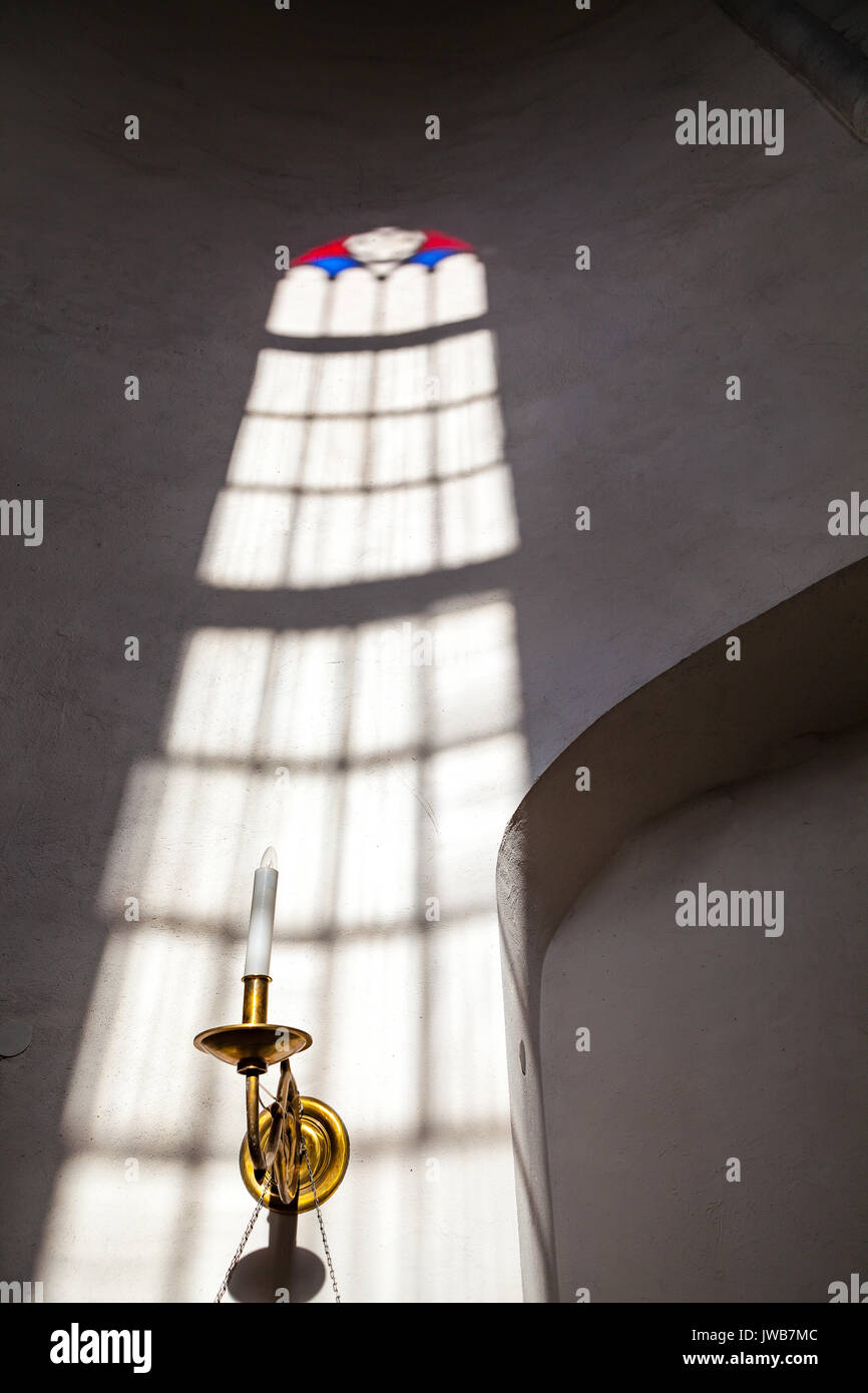 White church wall inside with rays of light going through stained glass window Stock Photo
