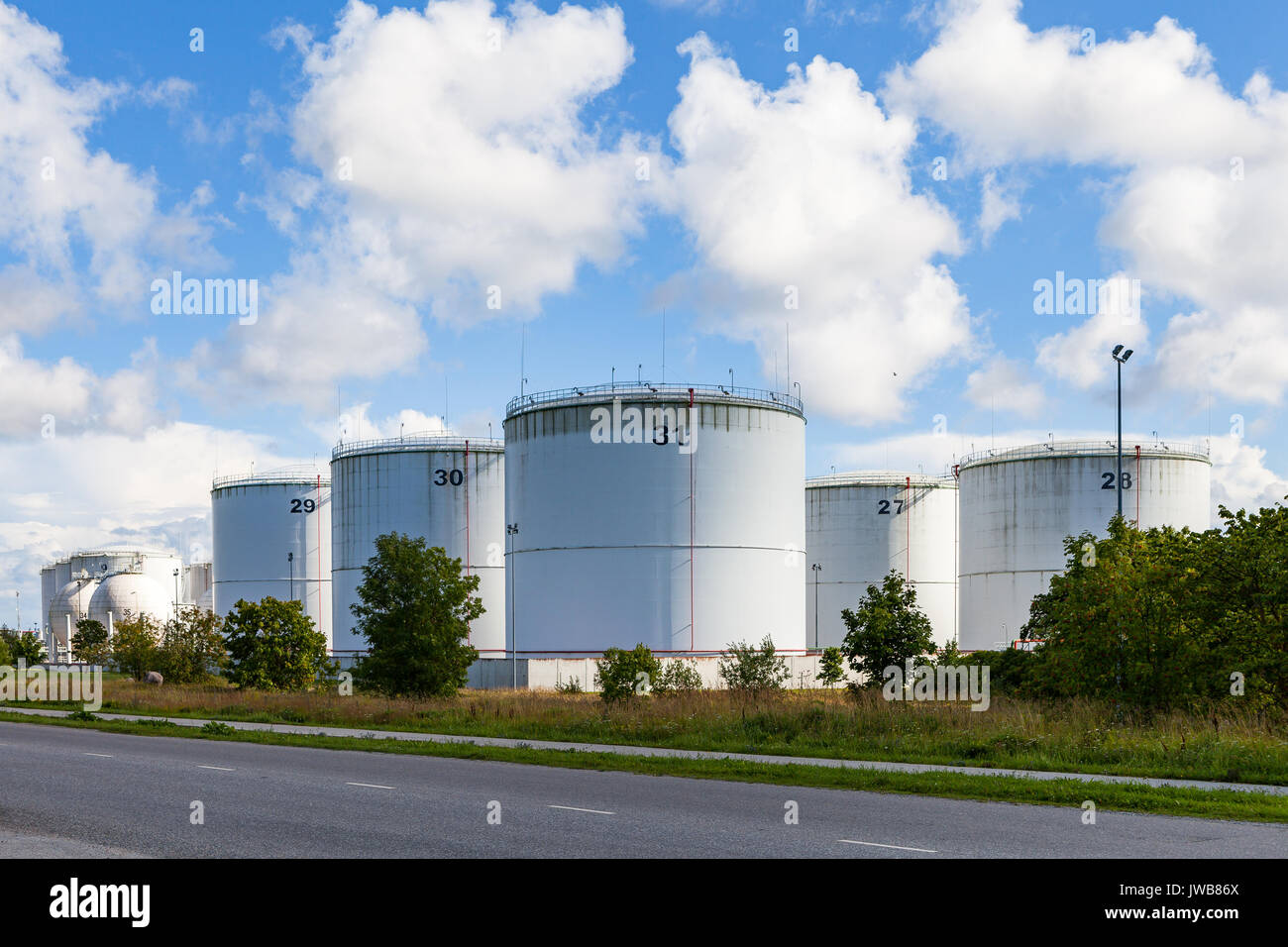Silver oil tanks on the green grass field. Blue sky with clouds Stock ...
