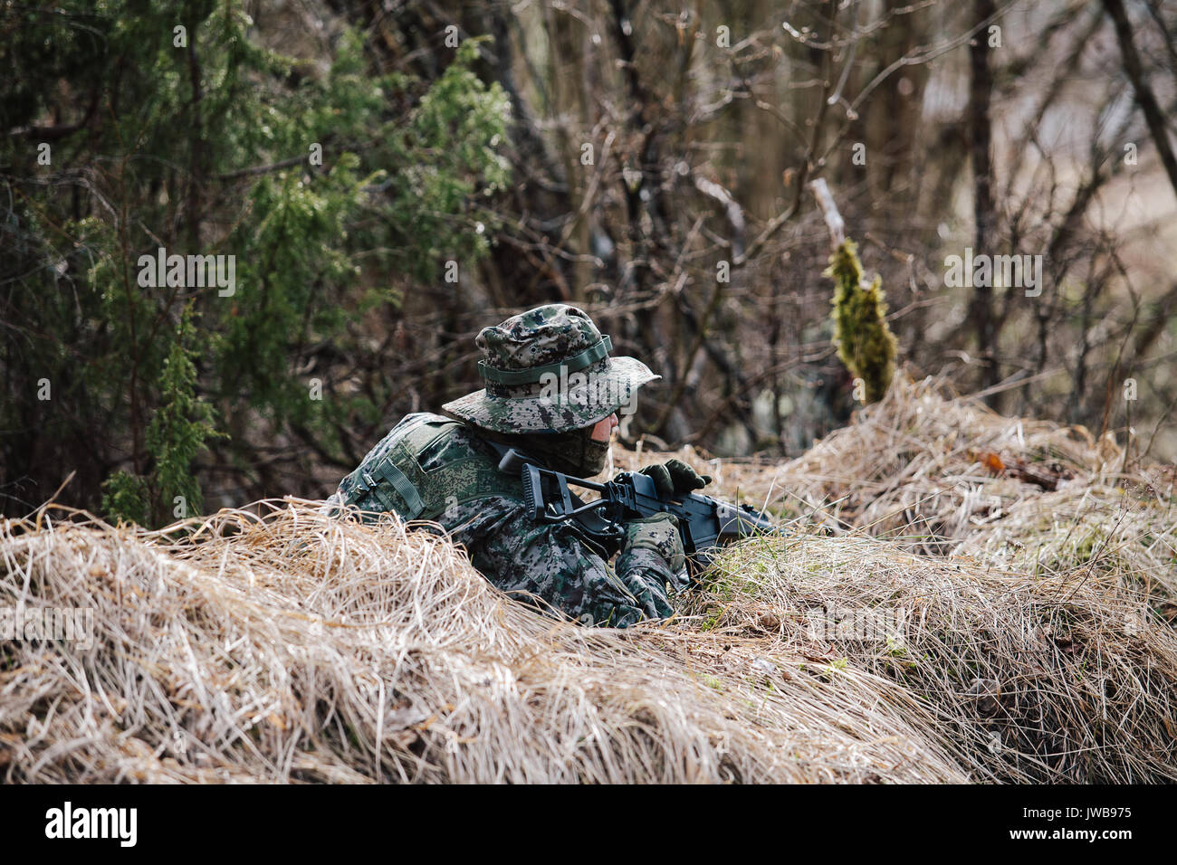 HUMALA, ESTONIA - 09 APR 2016: Soldier in camouflage with weapon protect his position. Military tactical airsoft game. Stock Photo