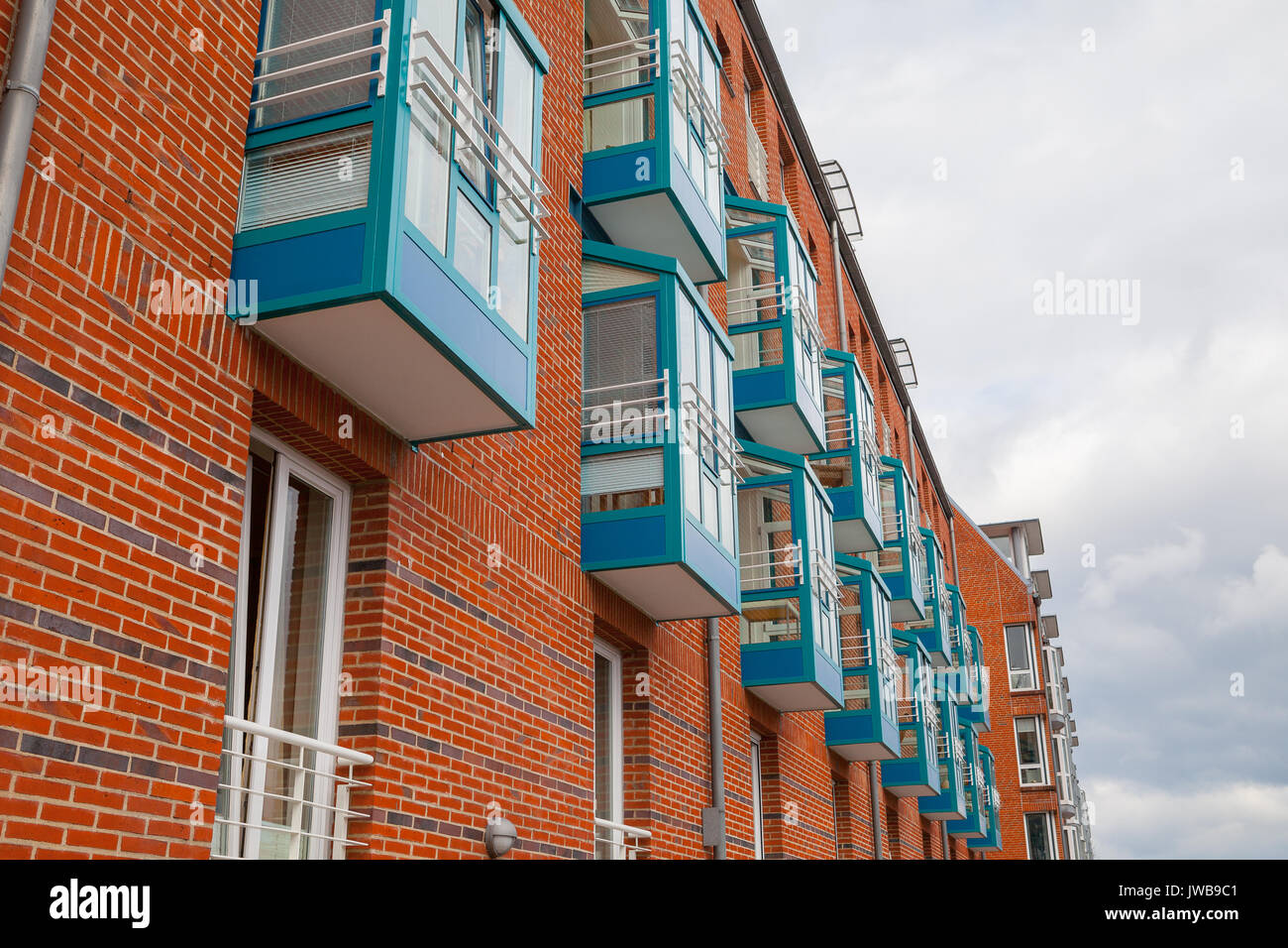 Fragment of new brick building wall with windows and blue balconies ...