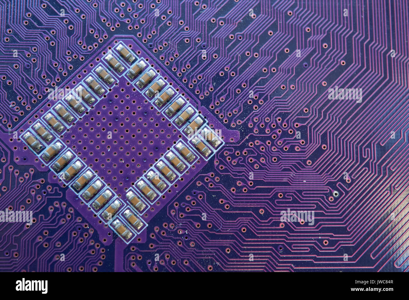 back side of computer motherboard with transistors chip soldered and lot of  tracks circuits. closeup shot in violet color palette Stock Photo - Alamy