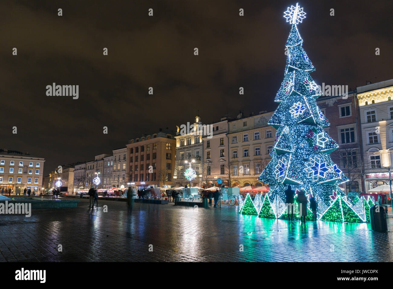 KRAKOW, POLAND - JANUARY 12, 2017: Unrecognized people walk along Christmas tree on Main Market square in old town at night. Krakow is the second larg Stock Photo