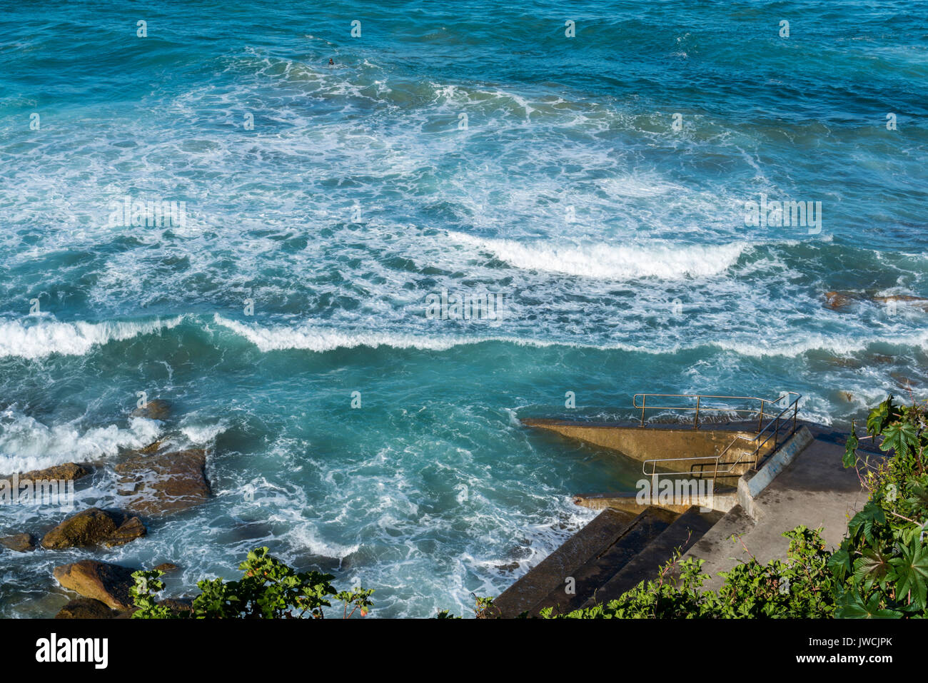 Turquoise water and white waves breaking on rocks and sea baths. Suitable as background or texture. Stock Photo