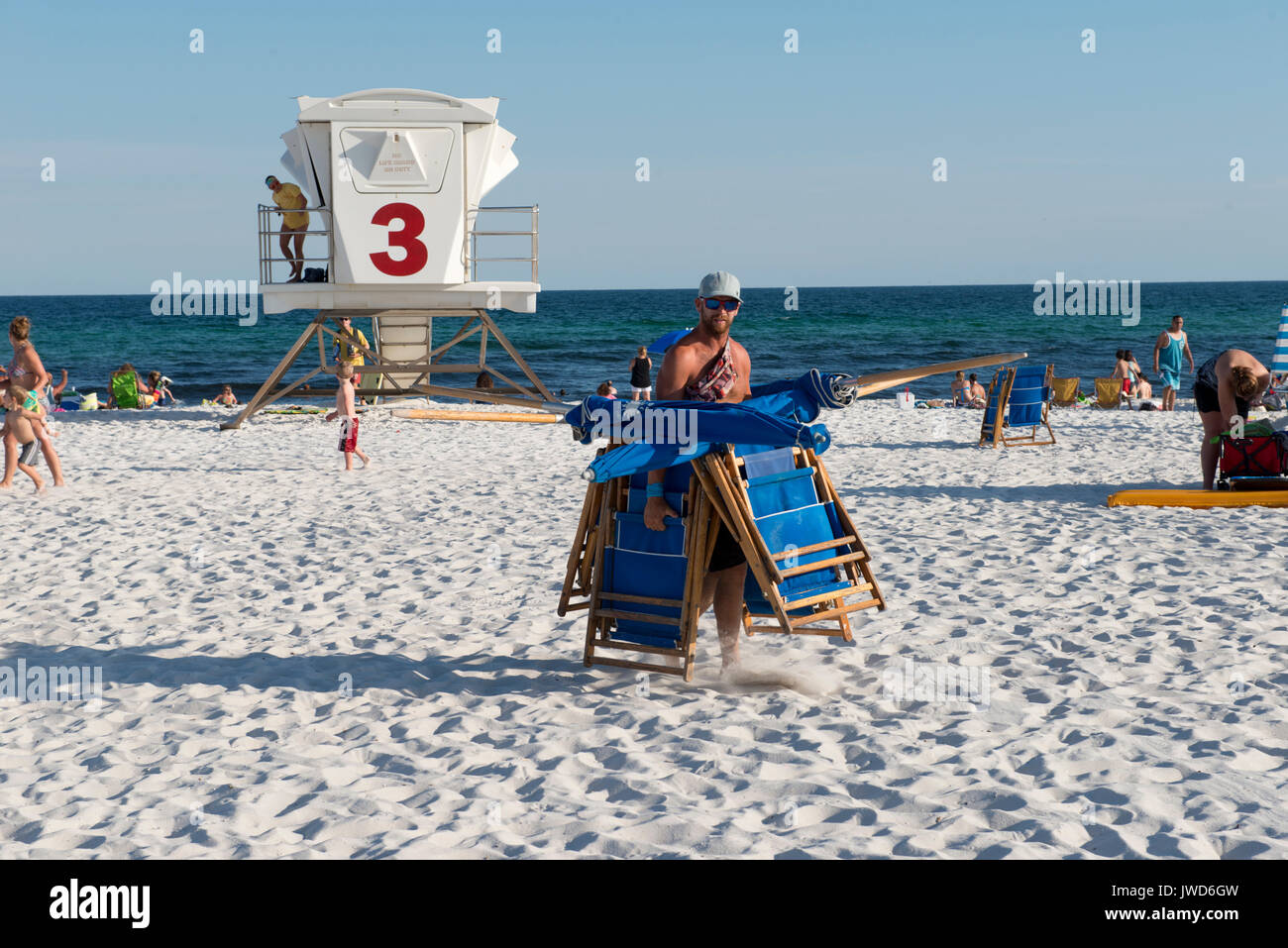 Male employee carries beach chairs to store them at the end of a work