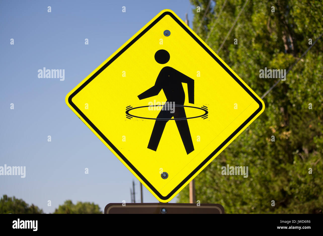 A bright yellow pedestrian crosswalk sign with a hula hoop drawn onto it. Stock Photo