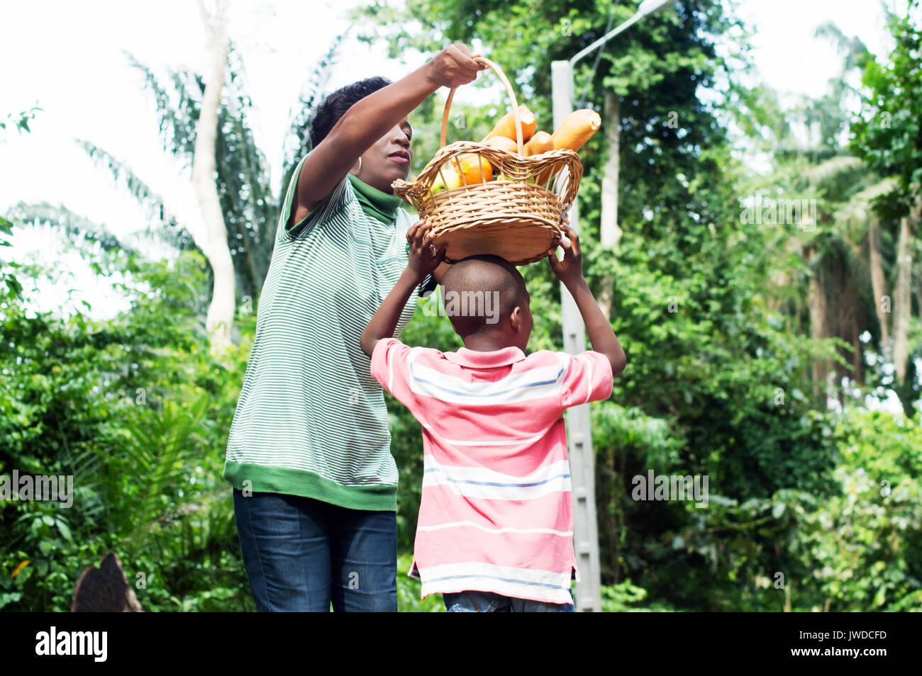 Mom puts the food basket on his son's head as he wants Stock Photo Alamy