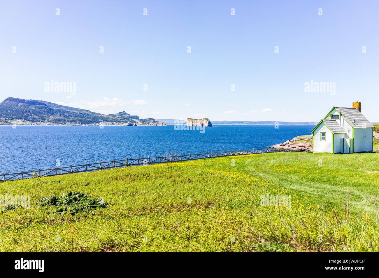 View of Rocher Perce from Bonaventure Island with ocean and house Stock Photo