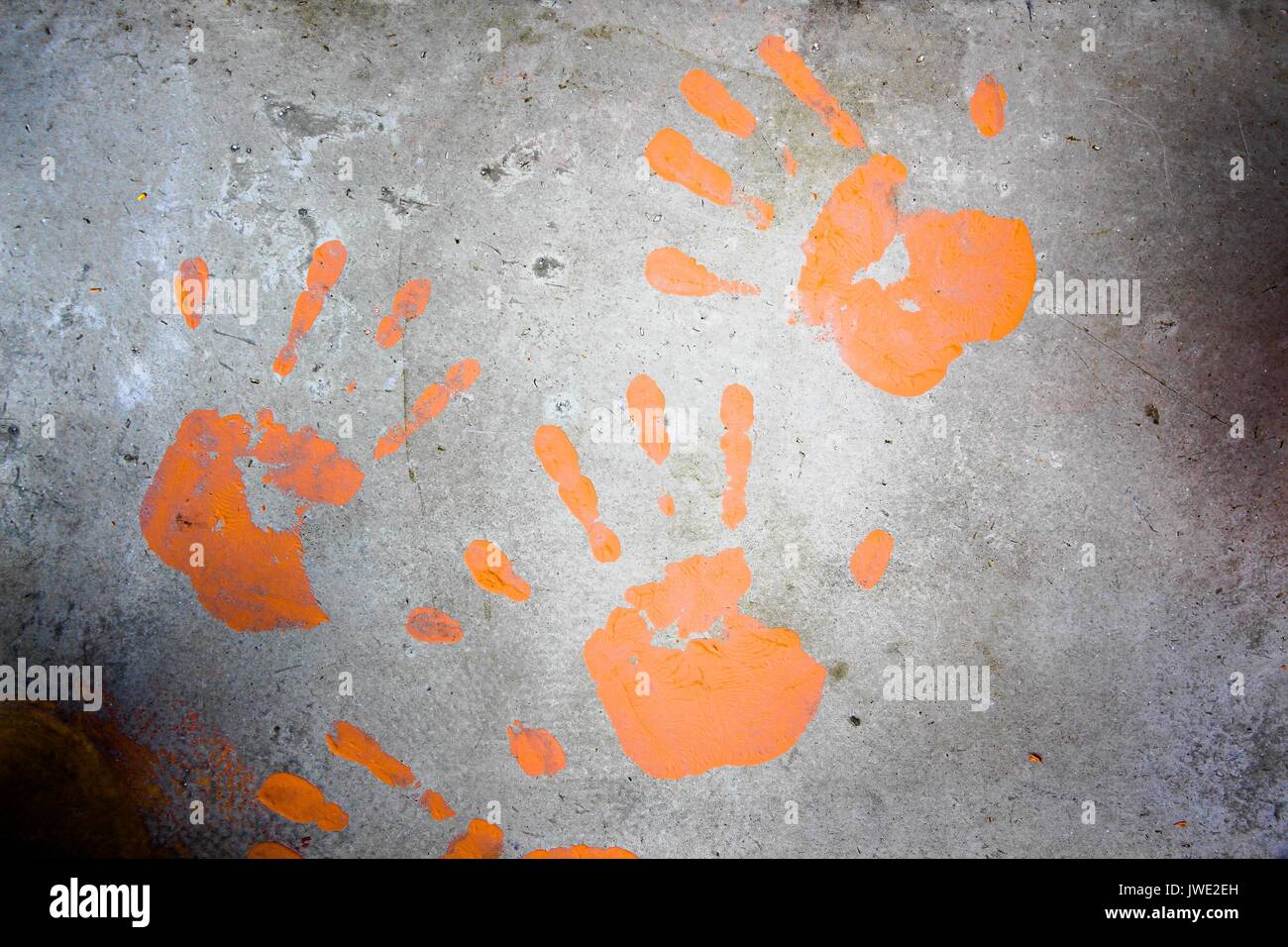 Handprints on the concrete floor are made with orange paint Stock Photo