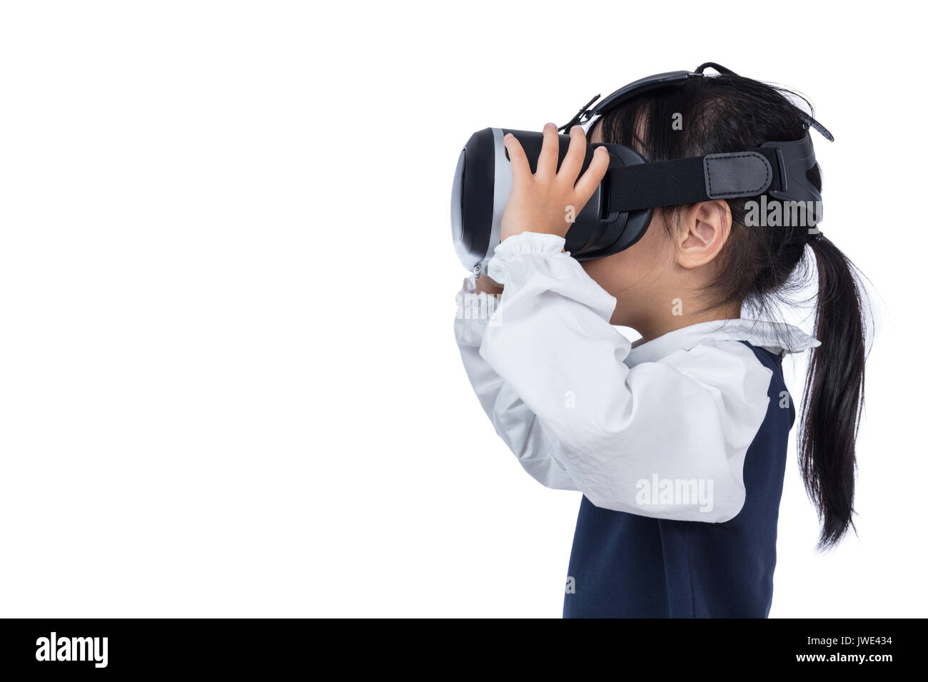 Asian little Chinese girl experiencing virtual reality via VR goggles in isolated white background Stock Photo