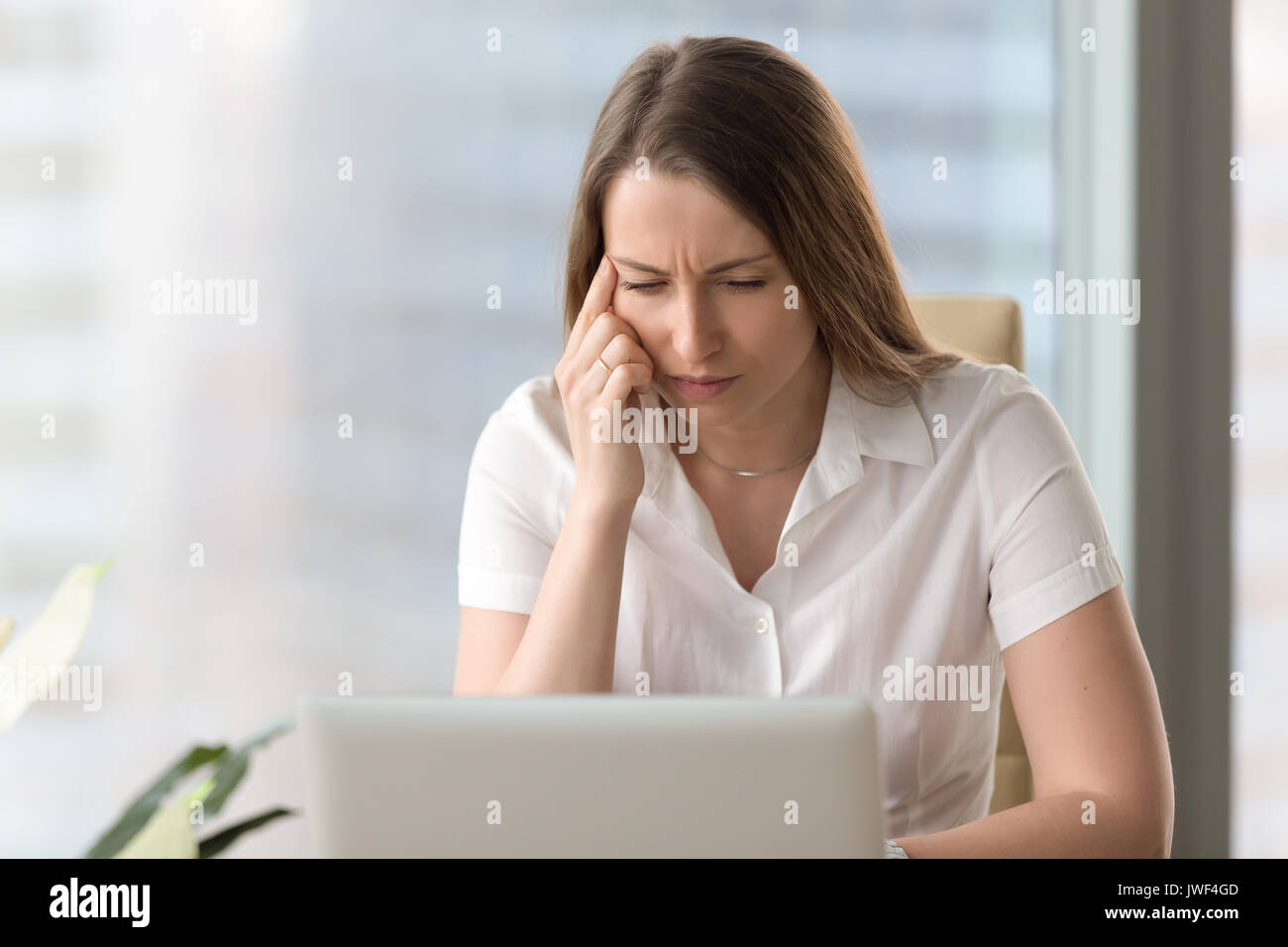Shortsighted businesswoman squinting eyes looking at laptop scre Stock Photo