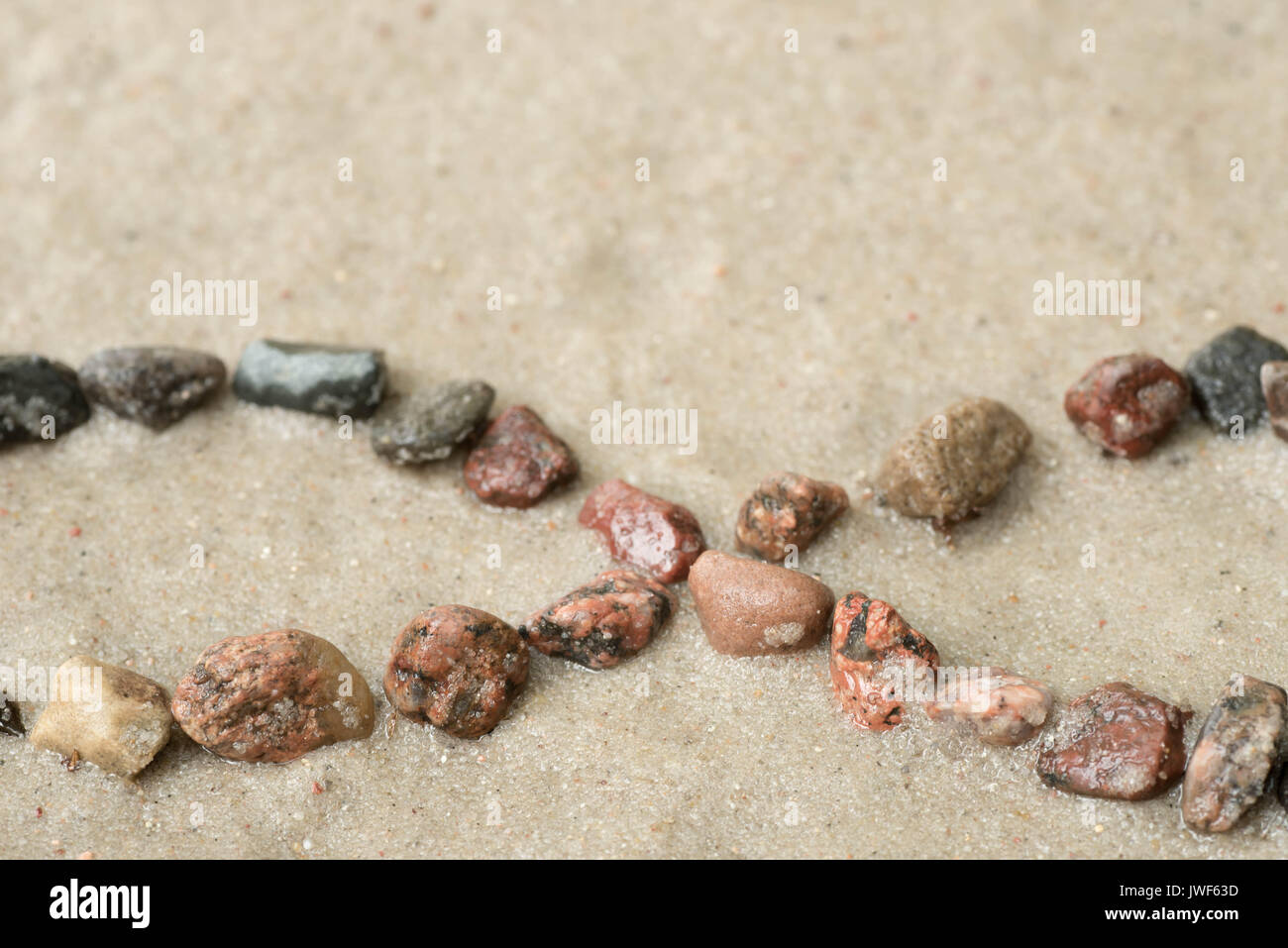 pebble infinity symbol on sand background selective focus Stock Photo