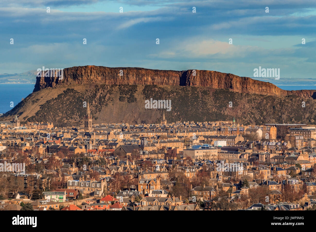 view across the rooftops of Edinburgh to Salisbury crags rock formation Stock Photo