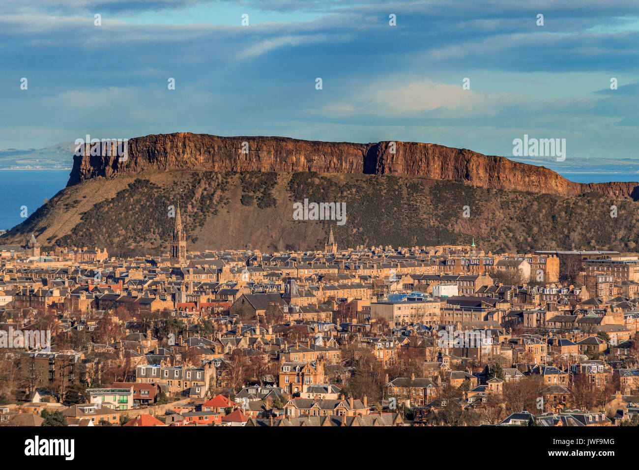 view across the rooftops of Edinburgh to Salisbury crags rock formation ...