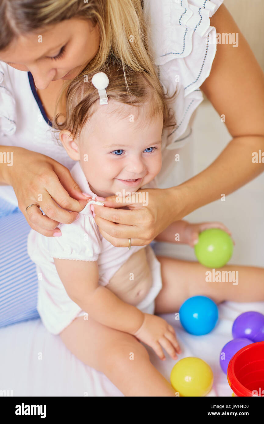 Mom mother dresses her baby child.  Stock Photo