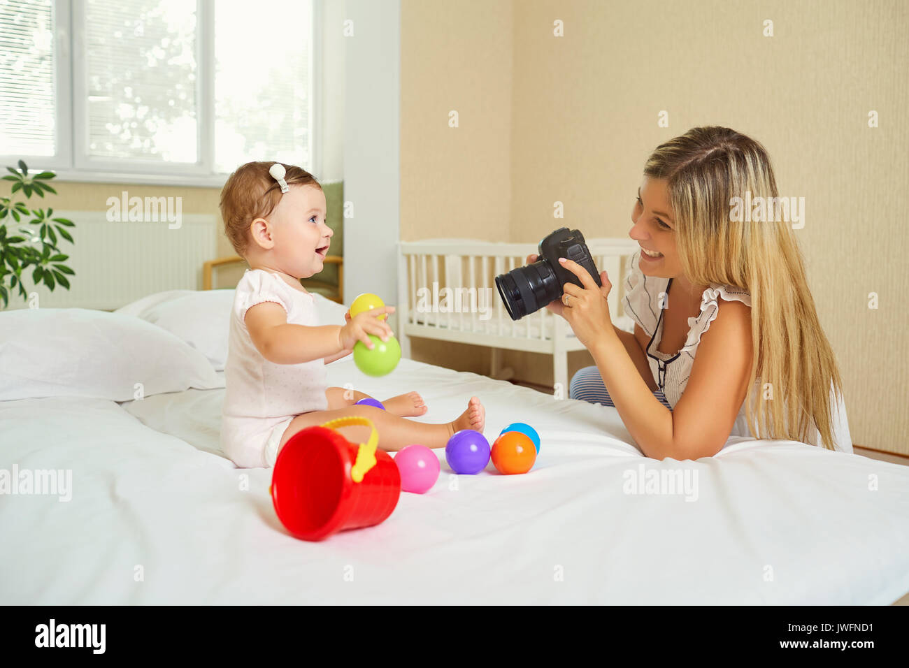 Mother  photographer photographing of her baby on camera. Stock Photo