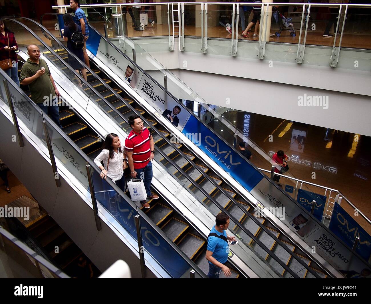 MANDALUYONG CITY, PHILIPPINES - AUGUST 4, 2017: Customers use an escalator to go up and down a mall. Stock Photo