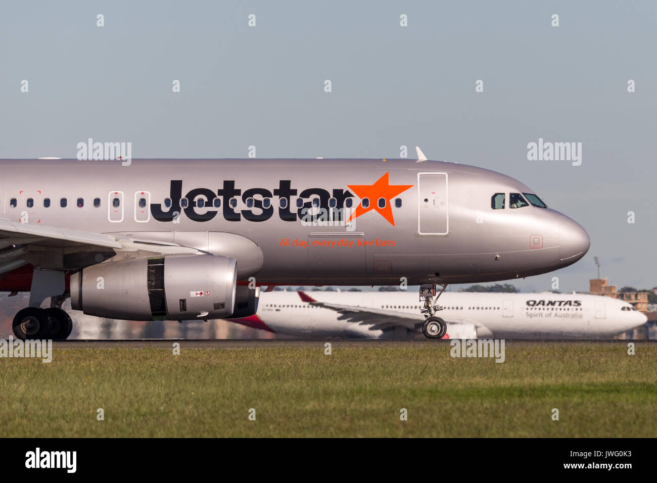 Jetstar Airways Airbus A320 airliner landing at Sydney Airport with a Qantas aircraft in the background. Stock Photo