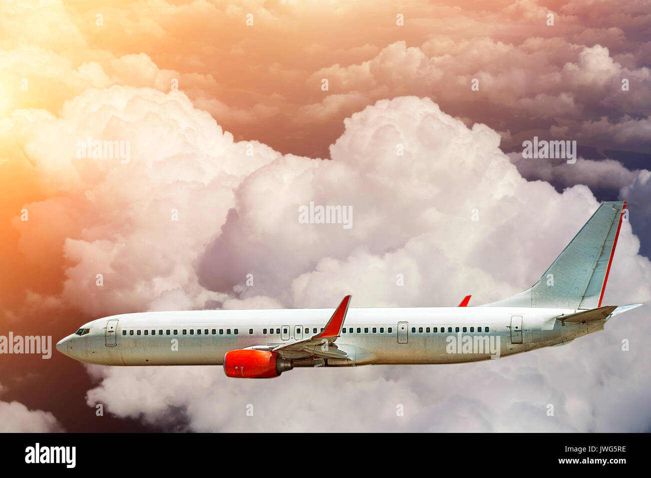 Airplane flying above clouds in sunlight. Stock Photo
