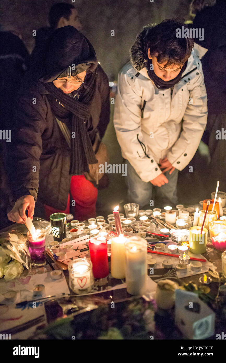 Grand son and grand mother lighting candle. Homage at the victims of Charlie hebdo killing in Paris the 7th of january 2015. Stock Photo