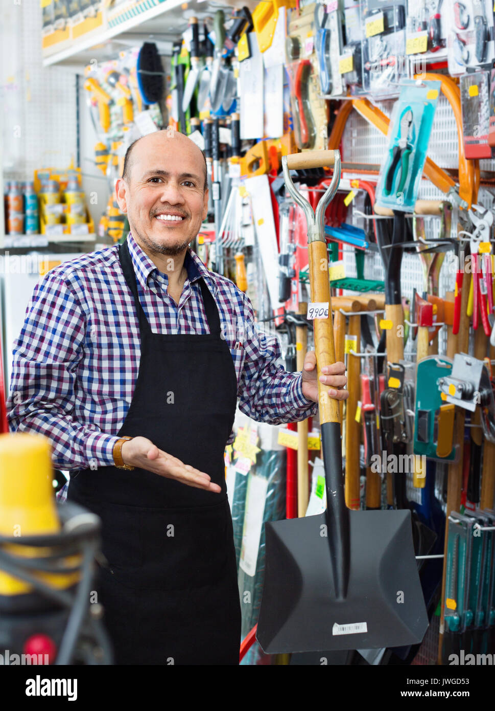 Professional senior salesman offering garden tools in building store ...