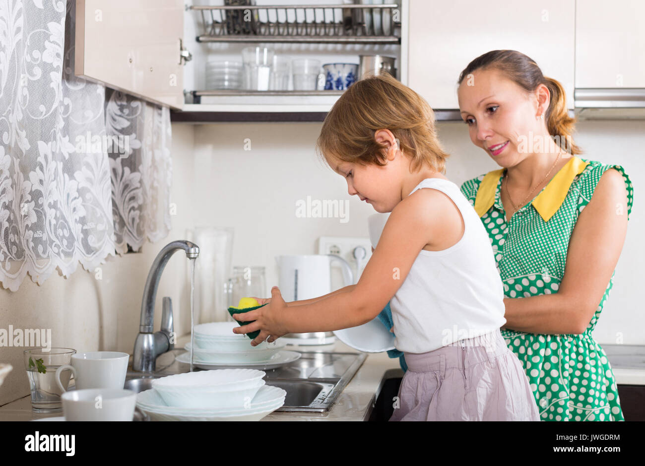 https://c8.alamy.com/comp/JWGDRM/little-daughter-helping-smiling-mother-washing-dishes-in-the-kitchen-JWGDRM.jpg