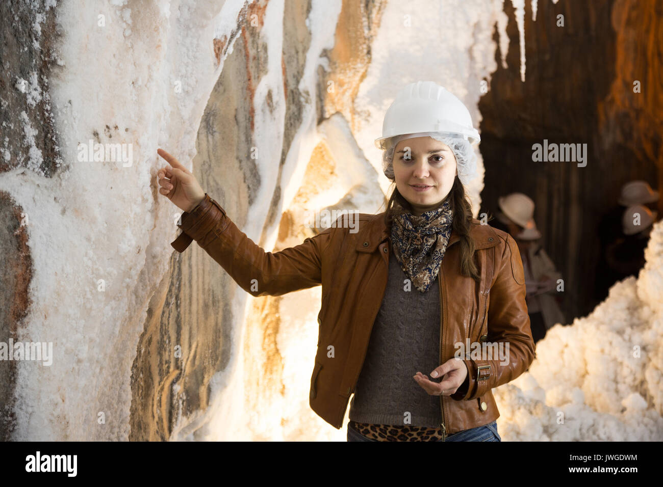 Brunette girl in helmet posing near stalactite at mine Stock Photo