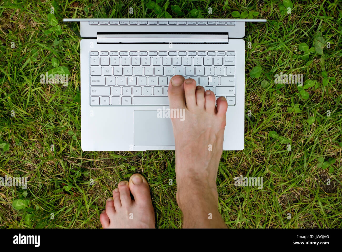 Close-up of male foot typing on laptop. Stock Photo