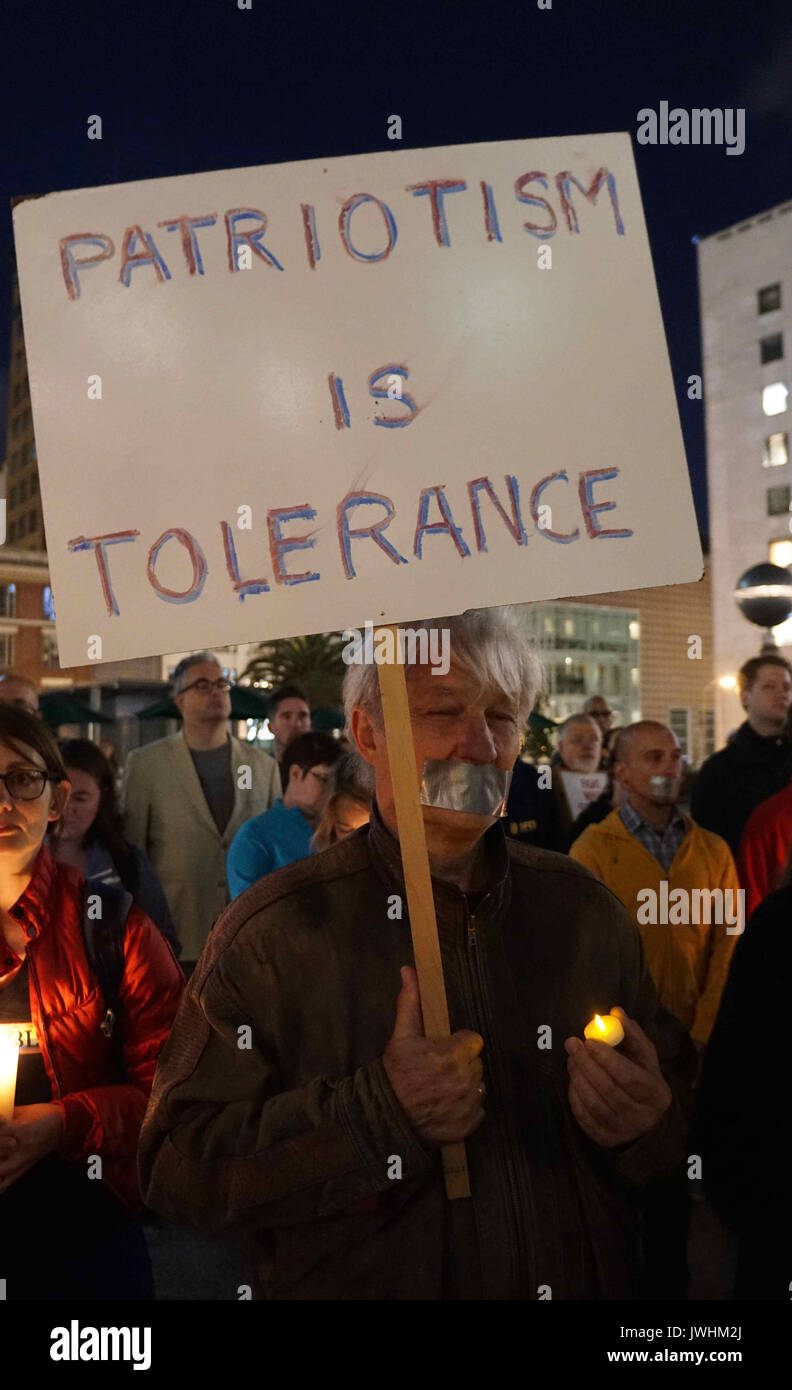 San Francisco, USA. 12th Aug, 2017. A man holding a sign reads 'Patriotism is tolerance' take part in a candle light vigil in downtown San Francisco, the United States, on August 12, 2017. Three people were killed and 19 wounded in Charlottesville, as a supporter of the so-called alt-right movement rammed his car into a crowd of protesters against a white nationalist rally. Then, a local group known as Indivisible SF, short for San Francisco, called for the vigil 'to stand in solidarity with Charlottesville.' Credit: Xu Yong/Xinhua/Alamy Live News Stock Photo