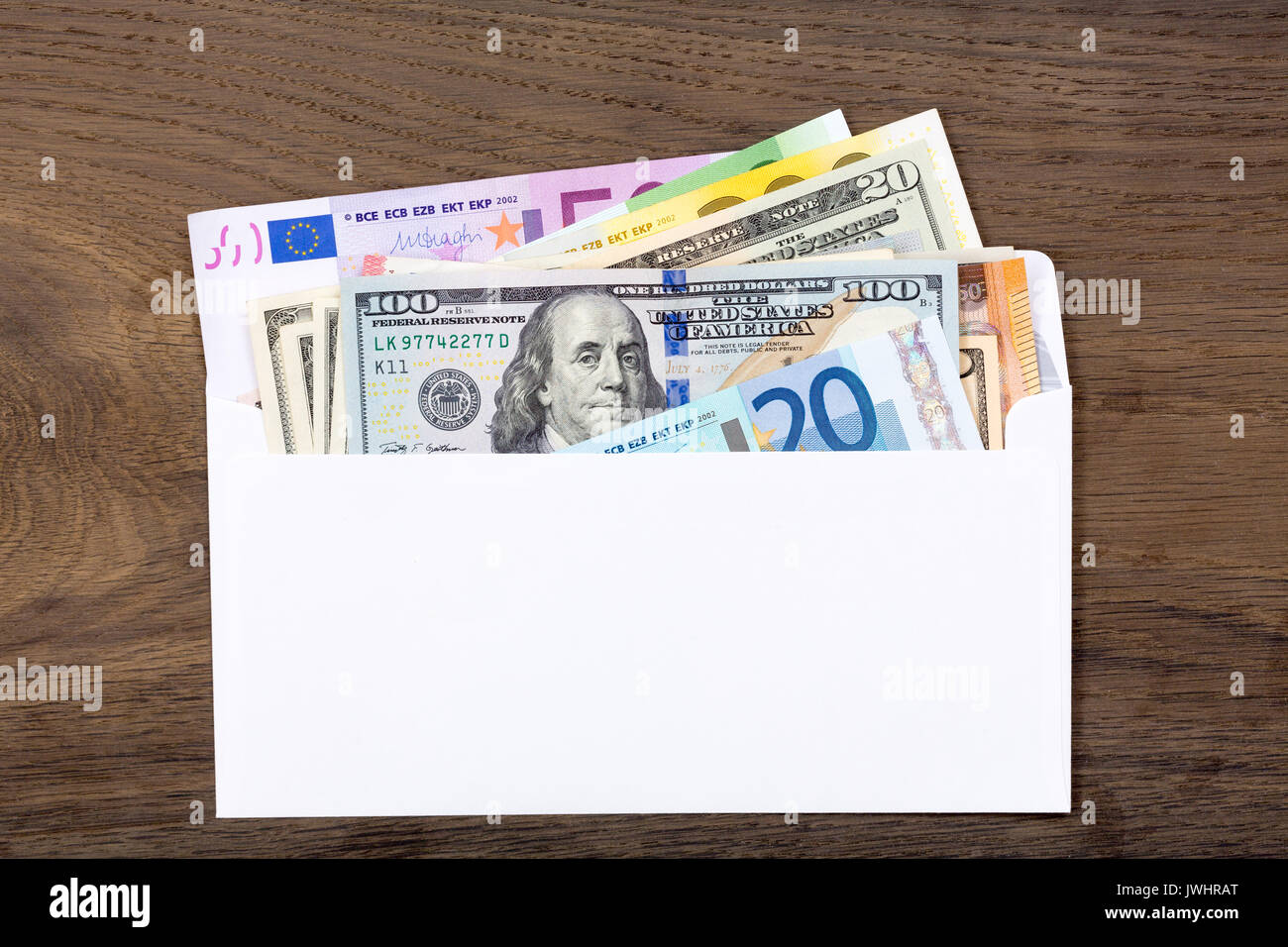 Dollars and euros in white envelop on wooden background. Stock Photo
