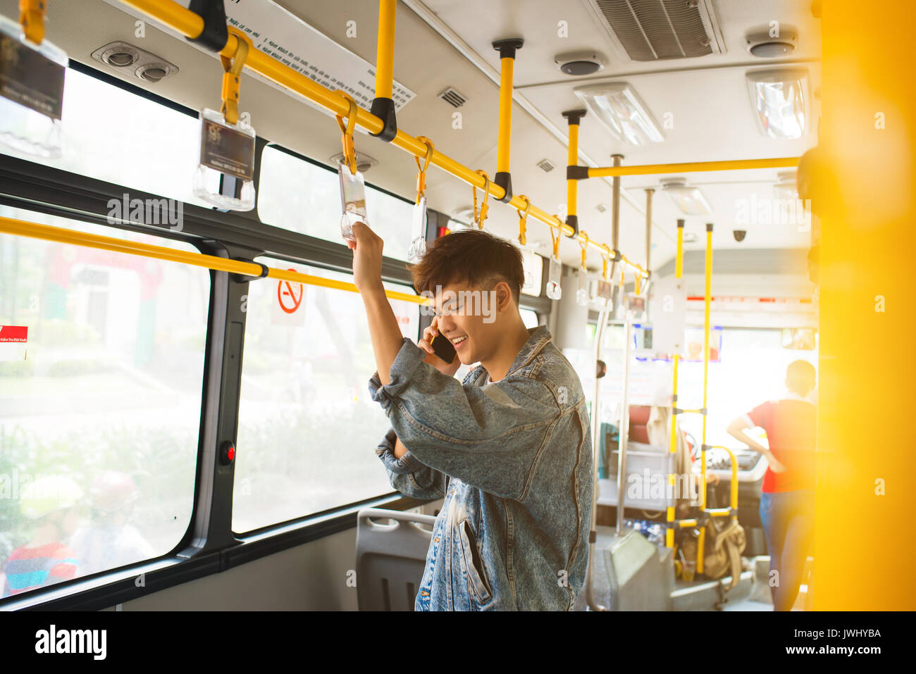 Handsome asian man standing in city bus and talking on mobile phone Stock Photo