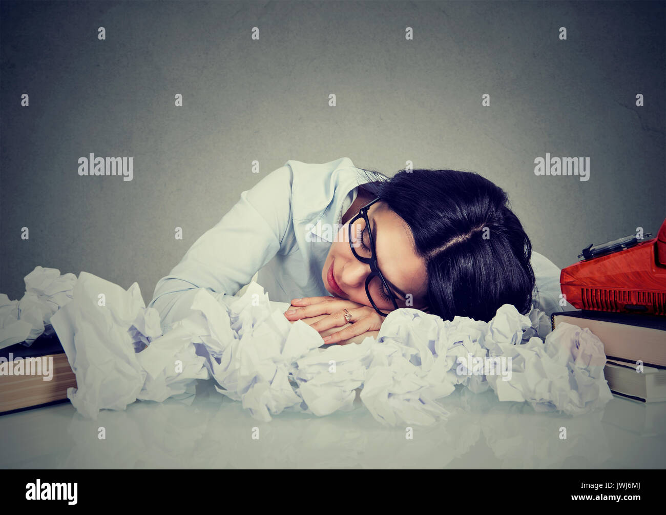 Young woman sleeping at her disorganized desk Stock Photo