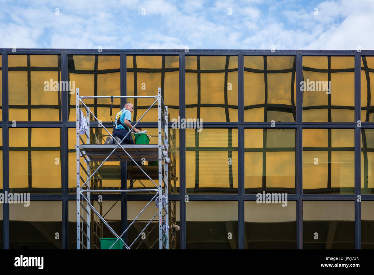 Windows cleaning work, man worker washing glasses windows at height in