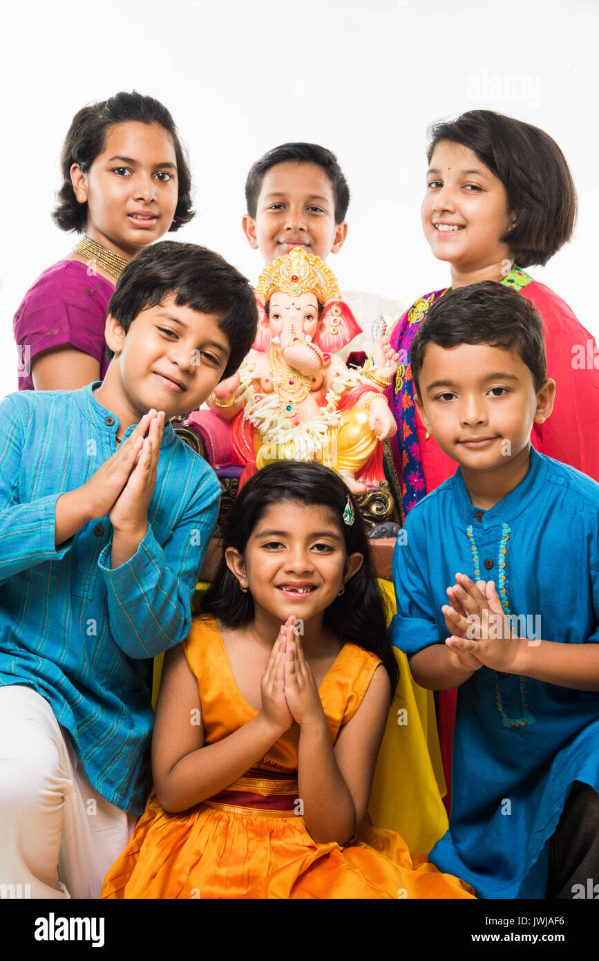 Indian Cute kids holding statue of Lord Ganesha or Ganapati on Ganesh festival or chaturthi, welcoming god. Asian small boys and girls with Lord Ganes Stock Photo