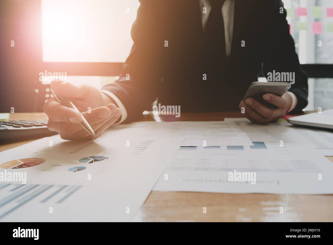 Businessmen are analyzed data from report using smartphone and laptop computer. Stock Photo