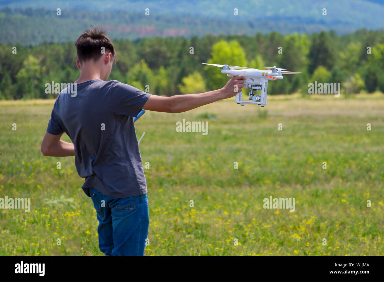 Teenager controling unmanned aerial vehicle (quadrocopter). Boy with quadrocopter drone. Stock Photo