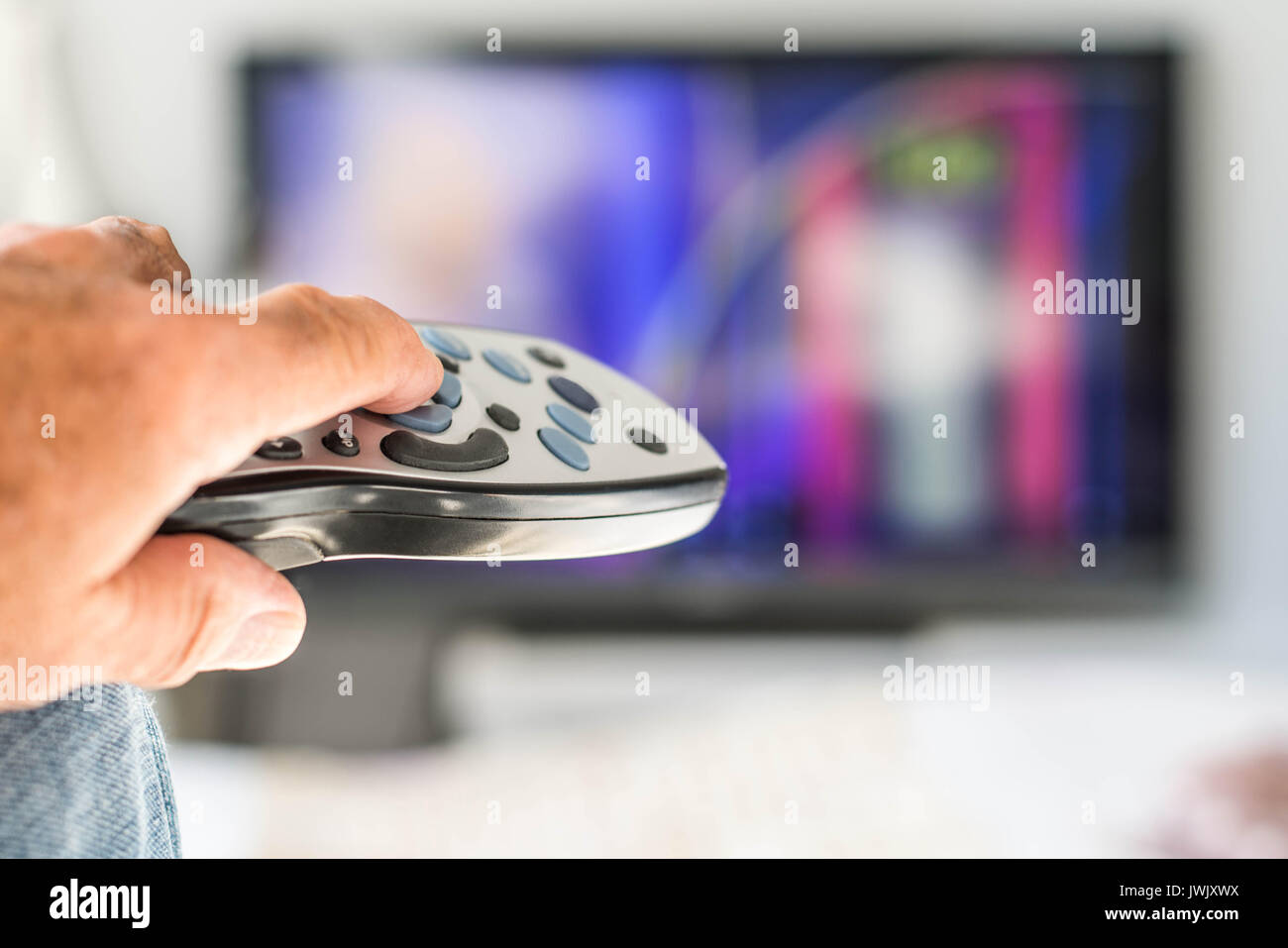 Holding and Pointing a TV Remote Control Box At a Television Selecting