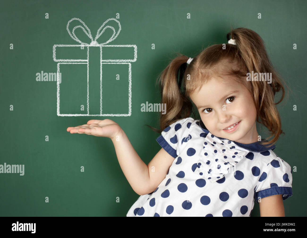 Smiling child hold drawn gift box near school blackboard Stock Photo