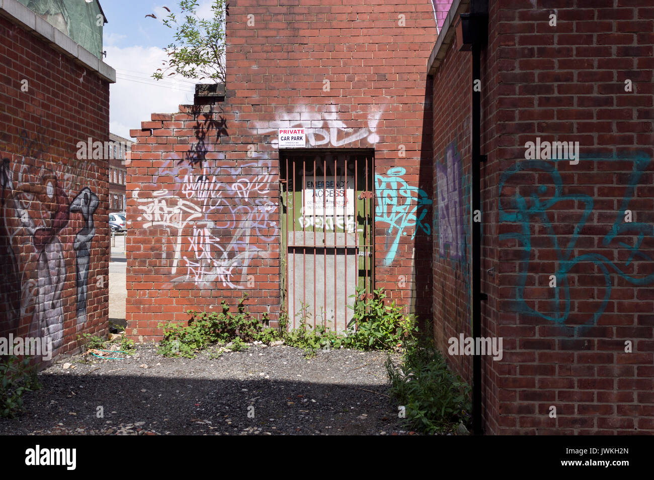 Abandoned Building, Derelict, Deserted, Brick Exterior, Graffiti, Debris, Weeds, Sealed Off, Iron Gate, Rundown, Secured, No Entry, Discarded, Writing Stock Photo