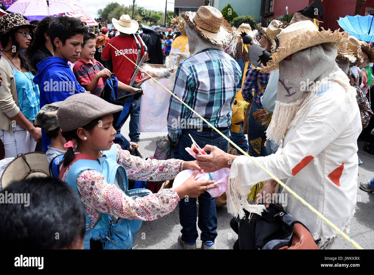 A participant dressed in colourful bizarre costume gives candies to the kids. Hundreds of people are seen participating during the annual parade of The Crazy Ones, a traditional  parade to celebrate welcome of the Holiday of San Antonio. Stock Photo