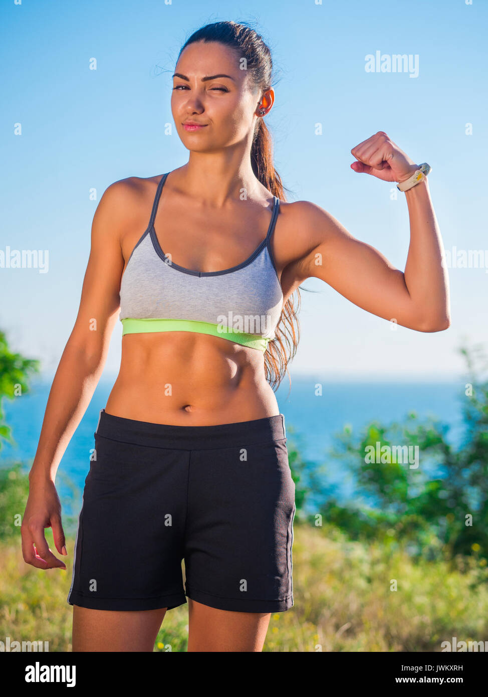 Confident female runner in sports bra and leggings standing on
