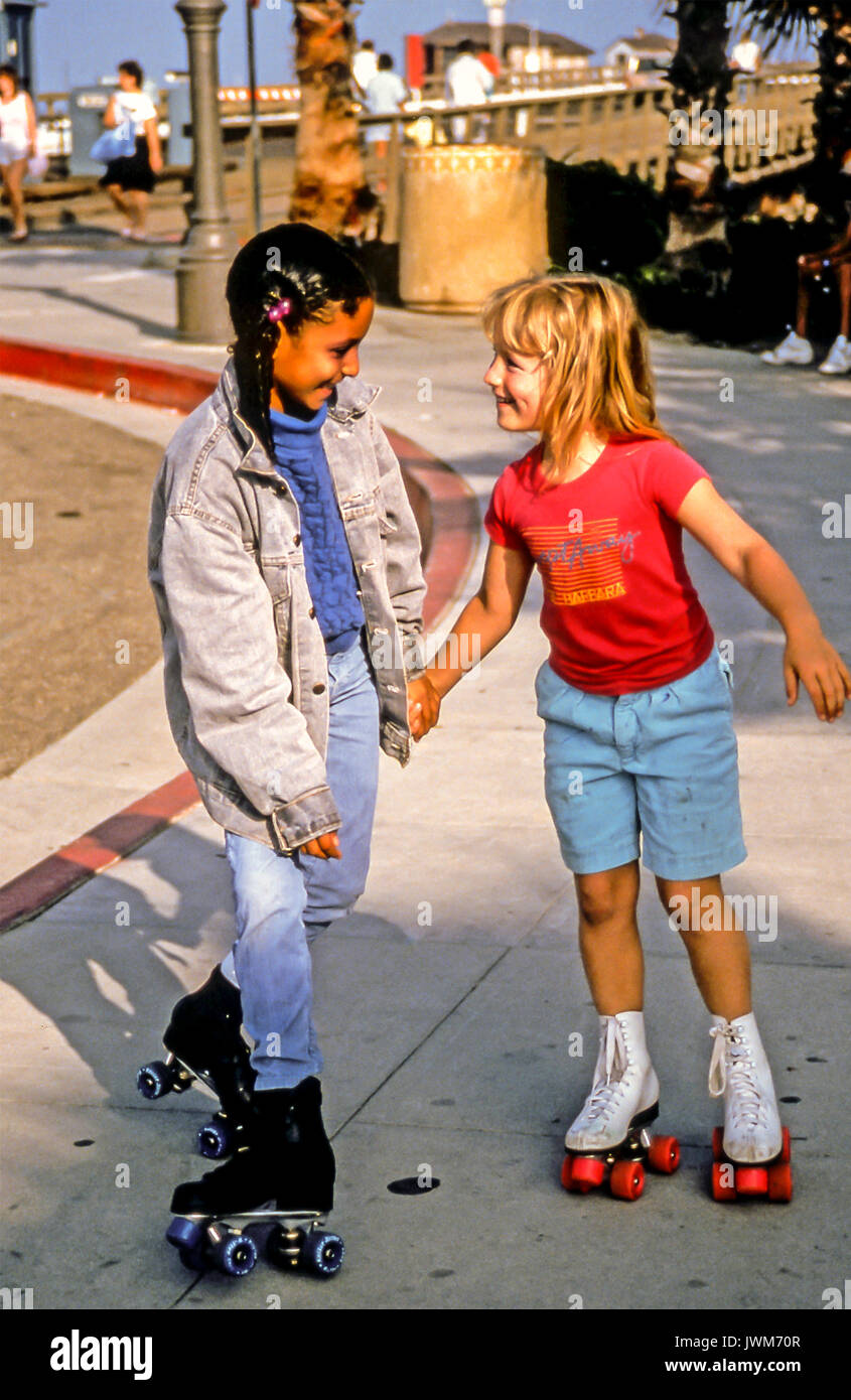 Two ethnically diverse girls 6-8-years old laughing and having fun together on roller skates in Santa Barbara, California Stock Photo